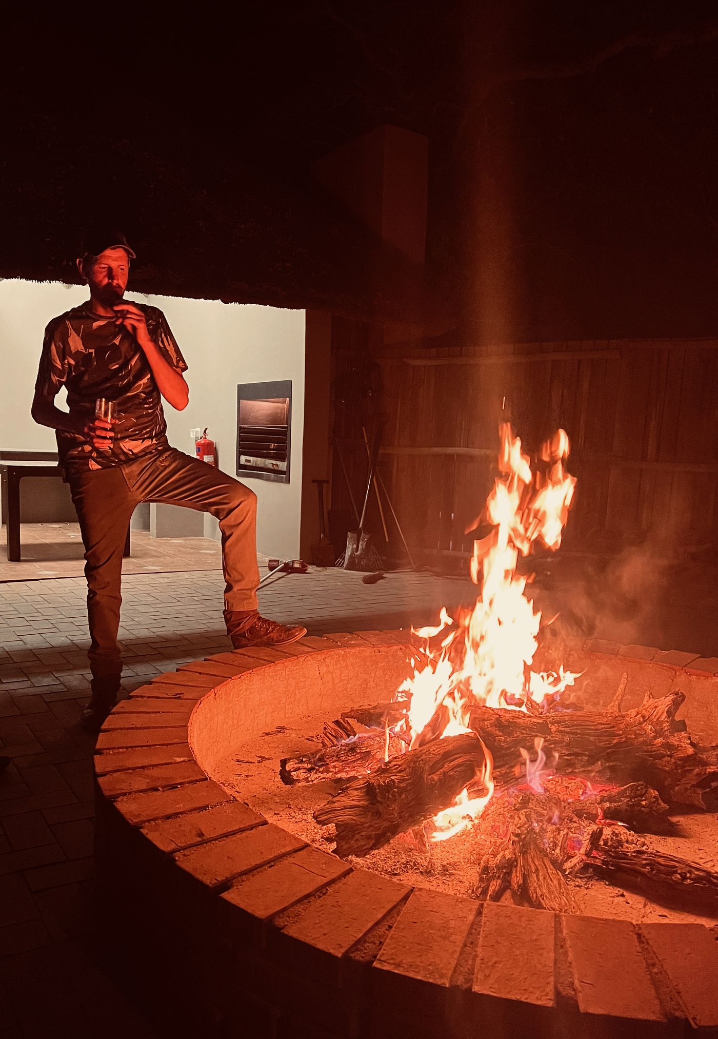 Guest standing by the fire pit at night at a JVZ Safaris camp